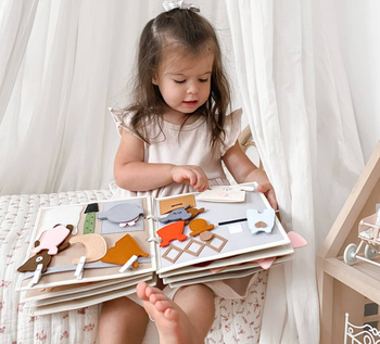 A child holding the felt activity book open on their lap.