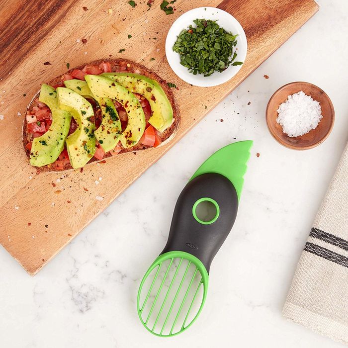 The slicer features a plastic knife edge on one end, a pit remover in the middle, and a slotted oval-shaped slicer on the other end.