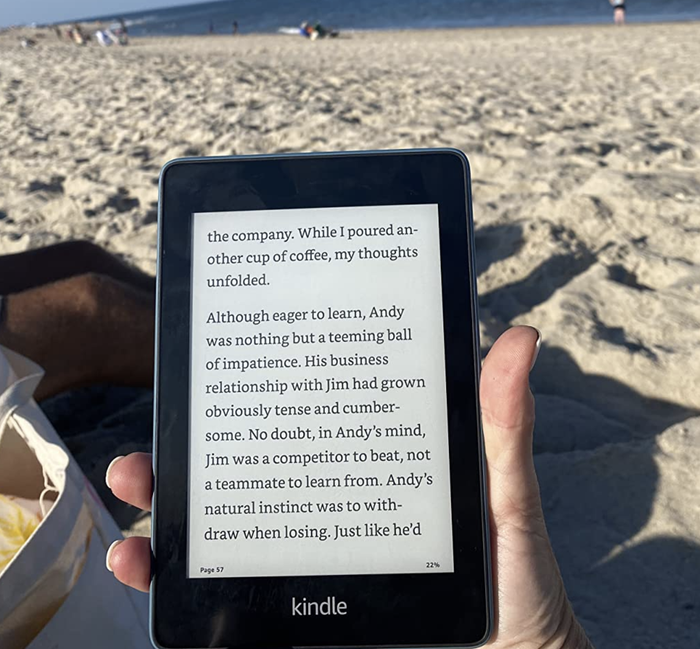 A reviewer reading from their Kindle while relaxing on the beach