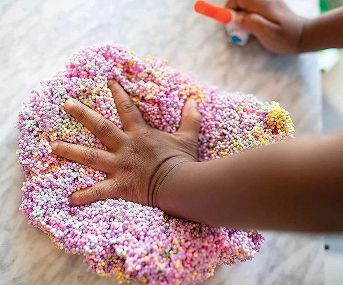 A child’s hand pressing playfoam into a table, enjoying the satisfying texture as they shape and mold it.