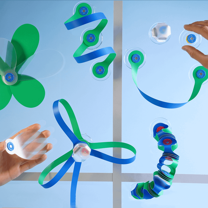 Blue and green Clixo pieces sticking to a window with suction cups