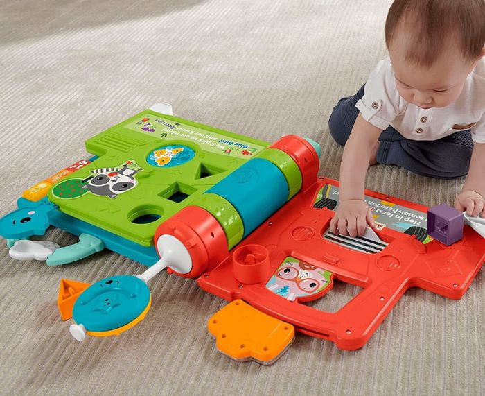 A child playing with a toy book on the floor
