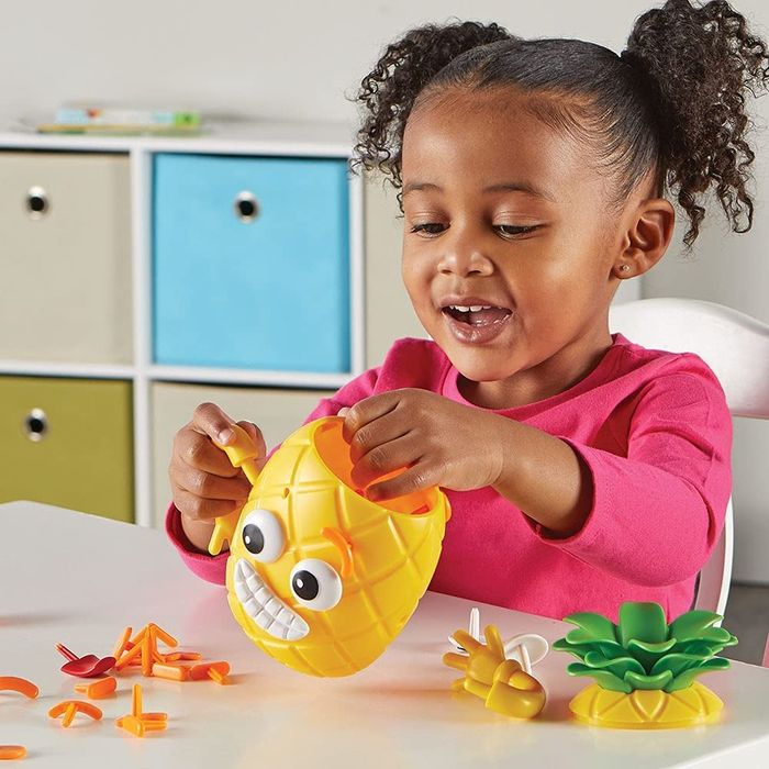 A child playing with a yellow pineapple toy featuring different facial expressions