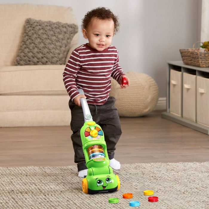 A child playing with a green plastic vacuum, filled with multicolored discs that add to the excitement of cleaning.