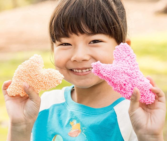 A child holding vibrant playfoam in each hand, ready to explore its squishy possibilities.