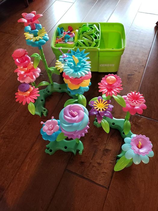 A reviewer's photo featuring plastic flower toys and a bucket