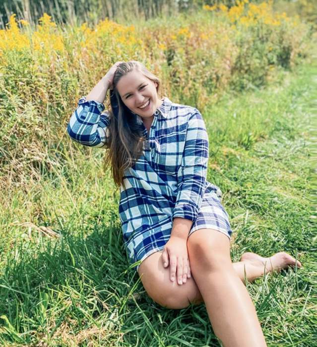 A customer review photo of them wearing the dress in blue plaid, captured in a grassy field.