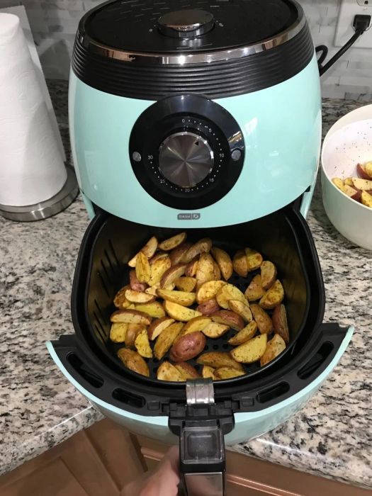 Reviewer fries golden potatoes in a blue air fryer