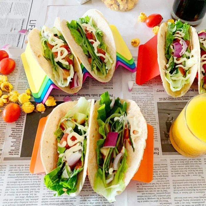 Red, orange, and yellow taco holders filled with soft shell tacos and all the classic fixings.