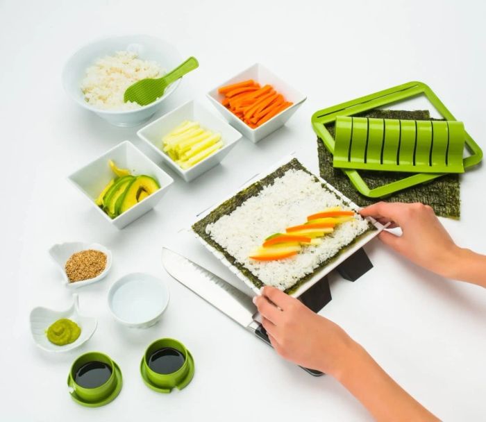 Hands assembling a salmon and cucumber roll using a DIY sushi kit