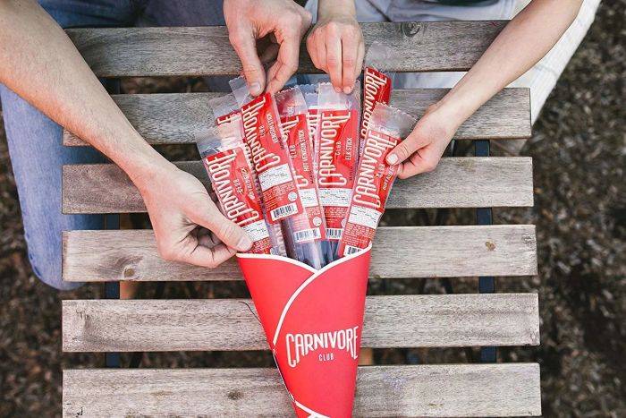 Hands removing jerky from a 'jerky bouquet' package