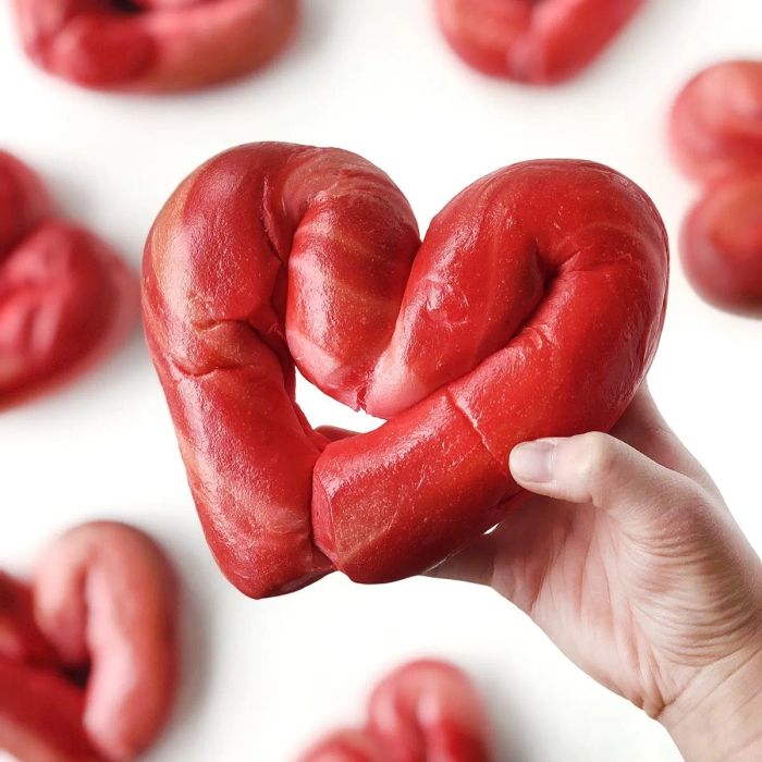 A hand holding a heart-shaped bagel