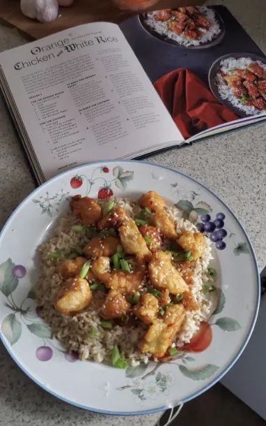 A photo of orange chicken and rice next to the corresponding recipe from the cookbook