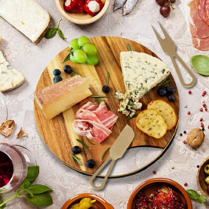 Wooden circular cheese board with gold accents, piled high with meats and cheeses