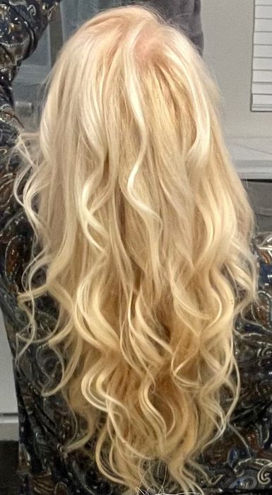 A person standing with their back to the camera, showcasing their long, wavy blonde hair.