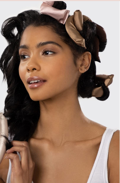 A woman using satin hair rollers for a heatless hairstyle, with product features listed alongside