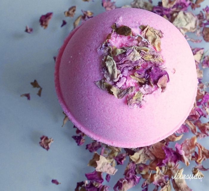 A pink bath bomb surrounded by potpourri.