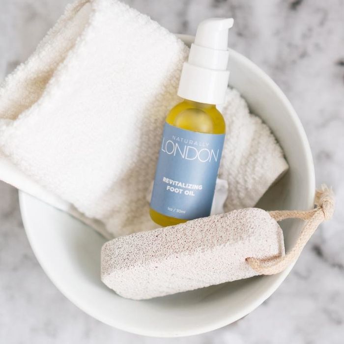 The foot oil bottle comes with a pumice stone and a white washcloth, all neatly placed in a wash bucket.
