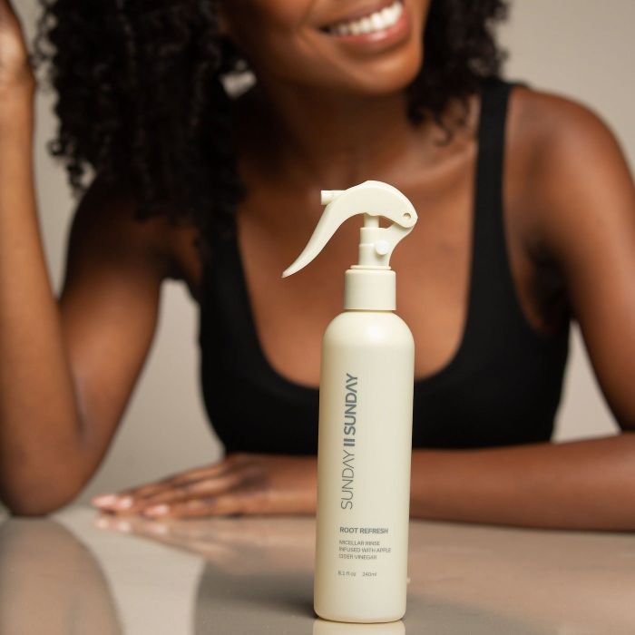 model posing behind a spray bottle of dry shampoo