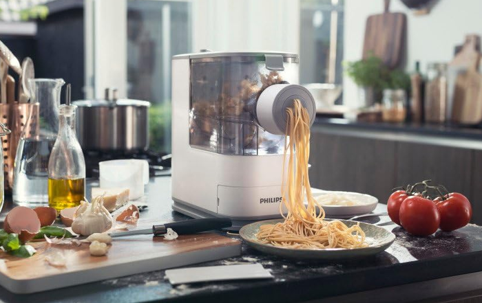 The pasta maker extruding spaghetti noodles.