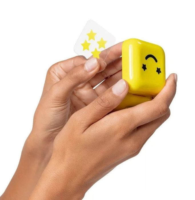 A hand holding the same yellow container with star-shaped yellow pimple patches inside