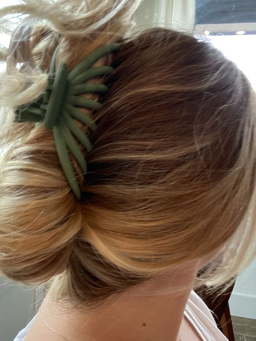 A woman has her hair styled into a bun, held in place by a large, elegant hair clip.
