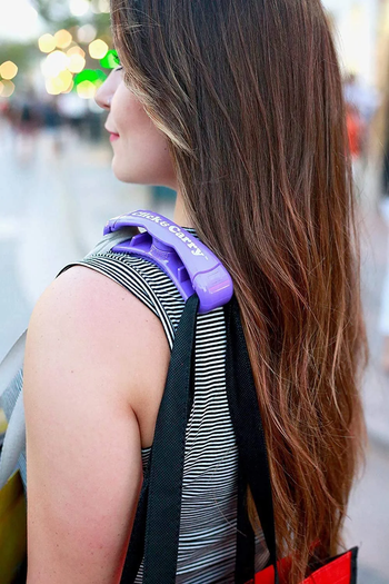 A model with a purple-handled Click & Carry gripping two heavy grocery bags.