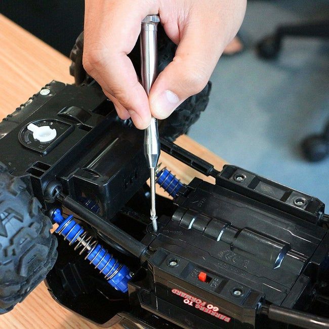 A person using a screwdriver to fix a toy car.