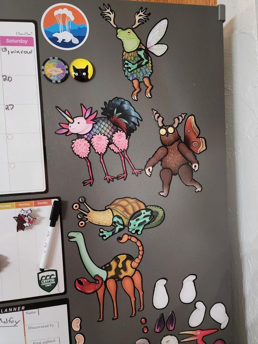 A fridge adorned with quirky animal magnets, a calendar, and a dry-erase note area with markers
