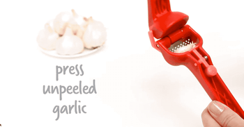 A gif showing the garlic press in action, mincing unpeeled garlic cloves.