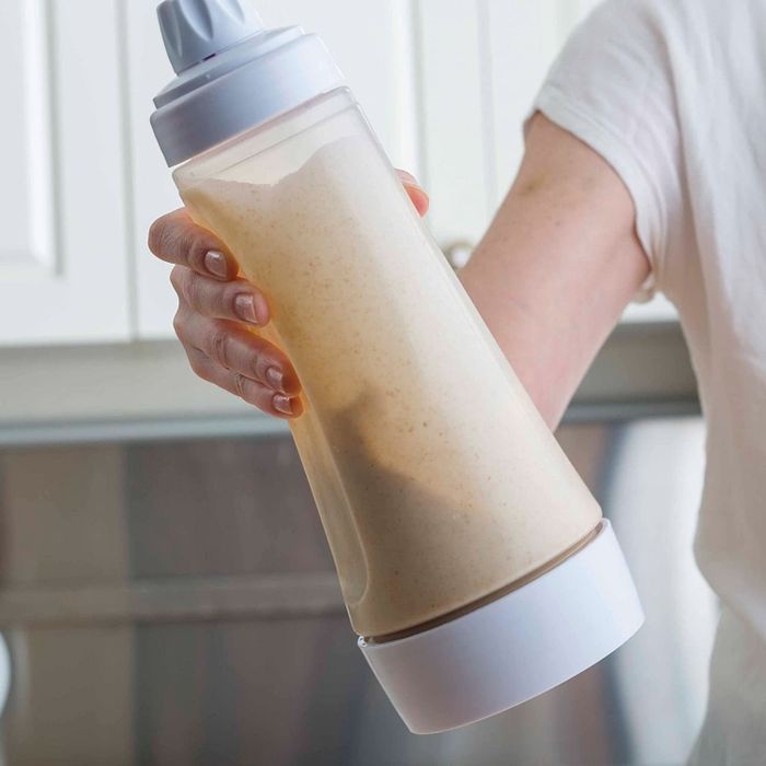 A person holding the Whiskware Pancake Batter Mixer featuring the BlenderBall Wire Whisk.