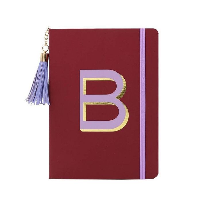 A deep maroon notebook featuring a striking purple and gold letter B design on the cover.