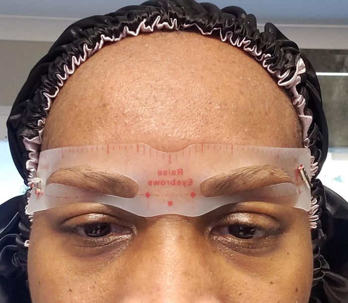 A reviewer applying one of the eyebrow stencils included in the kit.