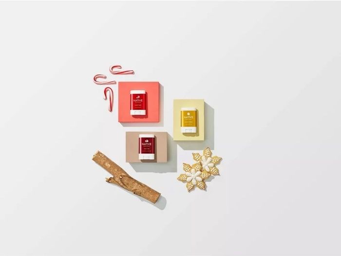 A bright orange, red, and yellow deodorant stick adorned with festive designs of sugar cookies and candy canes.