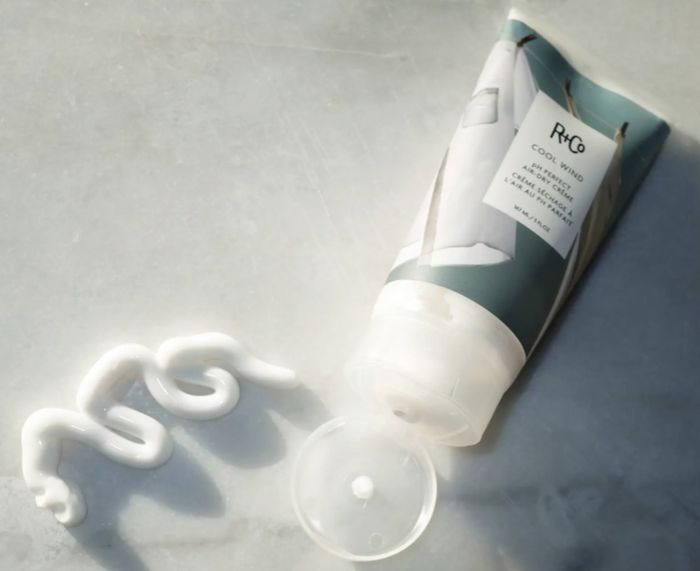 A close-up image showcasing the cream's texture placed beside its bottle.