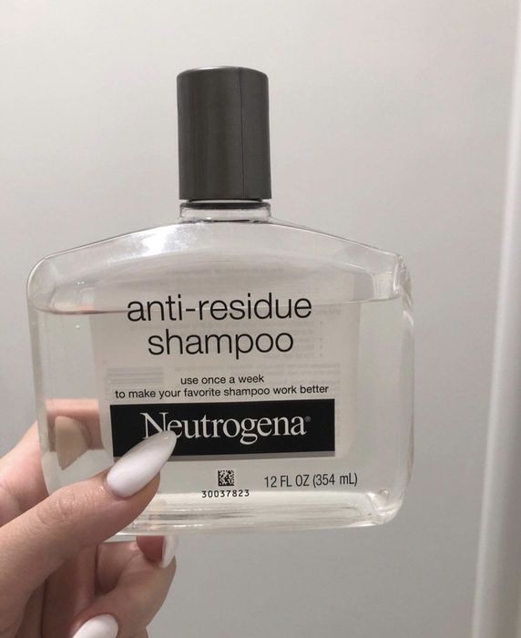 A person holding the bottle of clarifying shampoo.