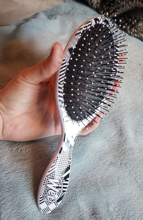 A reviewer holding the Wet Brush in hand.