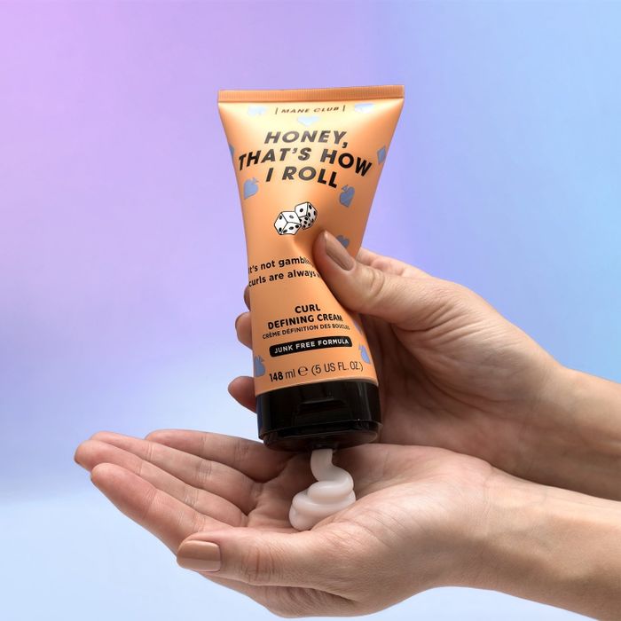 a lifestyle shot of the curl cream being squeezed onto a hand