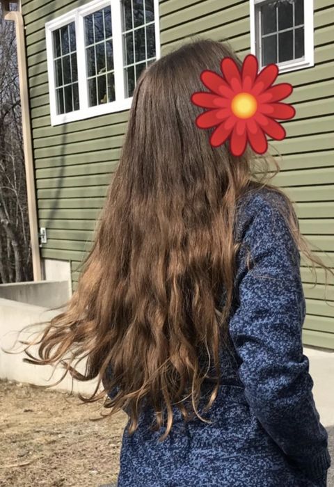 a person showcasing long, glossy, wavy hair after a year of using this mask