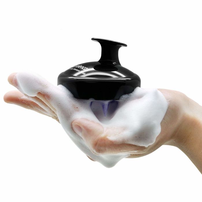 A palm-sized brush with lather in a hand, ready for use.