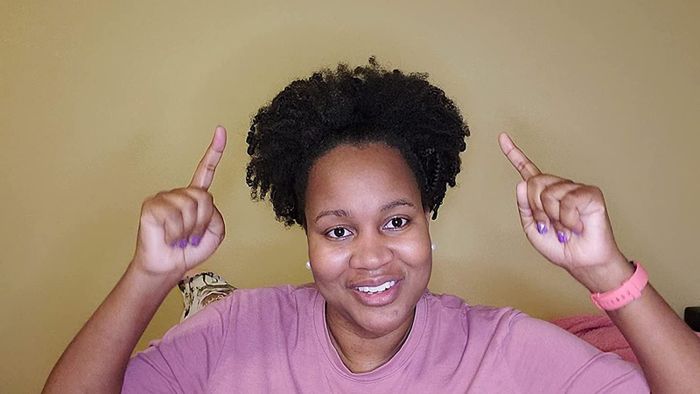 A reviewer pointing proudly to their defined curly hair.