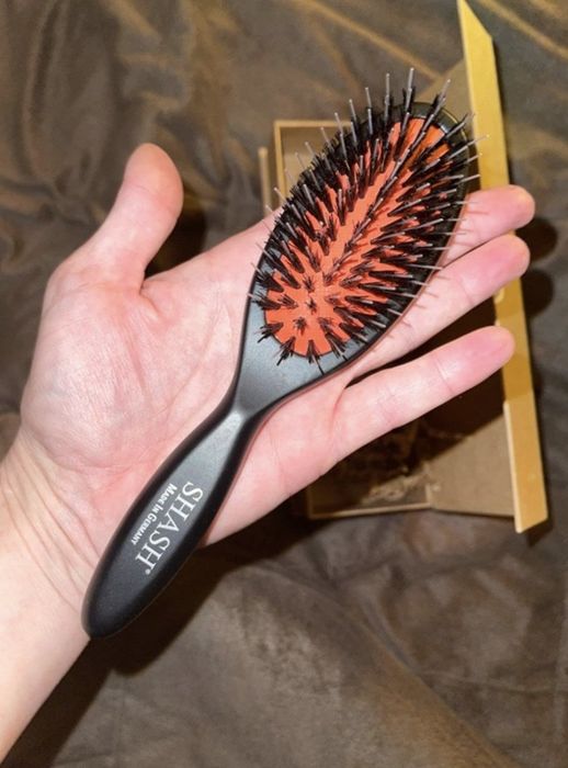 A person holding the black and red brush in their hand.