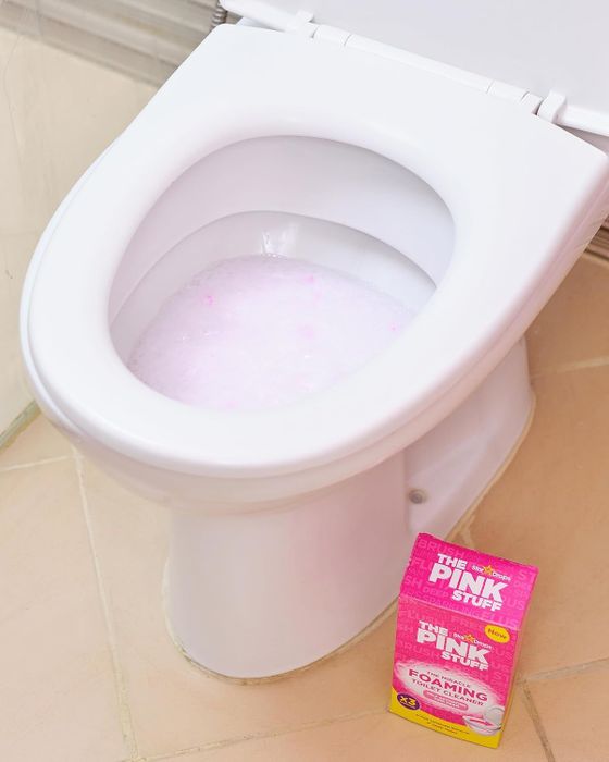 A picture of an open toilet with a cleaning product package beside it, showcasing a pink foaming toilet cleaner.