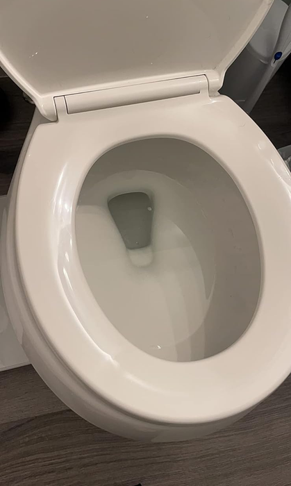 Another reviewer shows the inside of a clean, white toilet bowl with the Kaboom system installed.