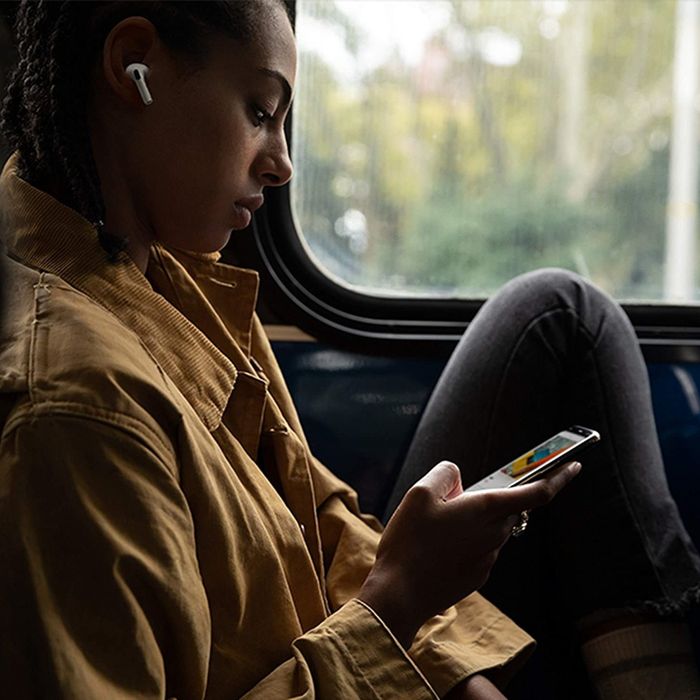 a person modeling the AirPods while holding a smartphone