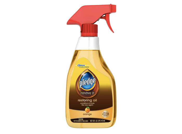 A bottle of Pledge Revive It restoring oil with an orange fragrance, designed to condition wood surfaces, complete with a spray nozzle