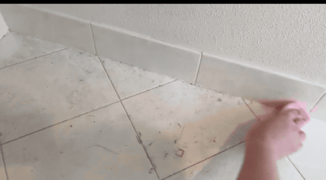 A gif showing a reviewer wiping dust off a tile floor with a damp duster sponge, revealing dust collecting on the ridges.