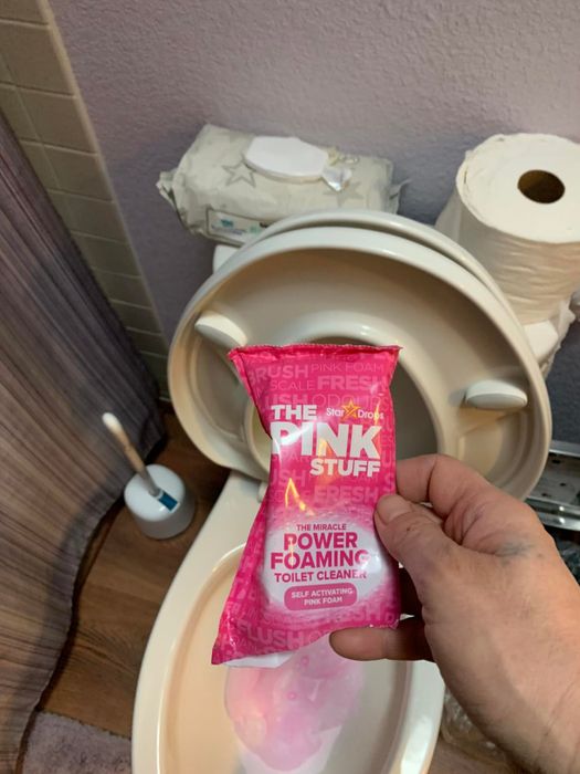 A reviewer holding a pink packet labeled with the brand name.