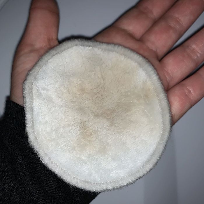 a reviewer’s hand holding a used cotton round with makeup residue
