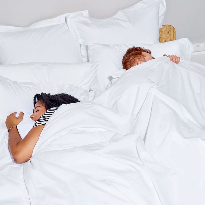 two models sleeping in a bed adorned with white sheets